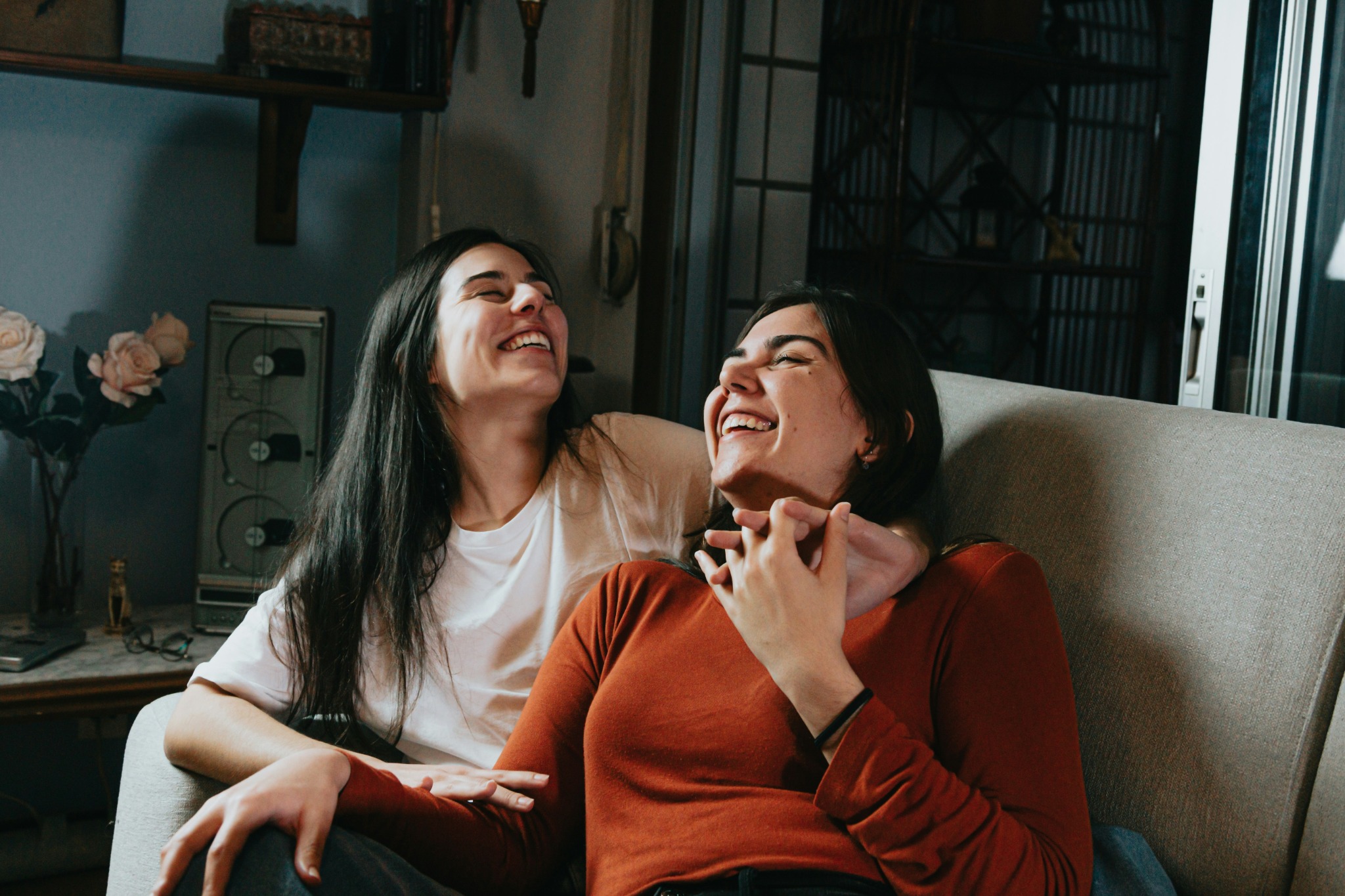 Two women laughing together on a sofa