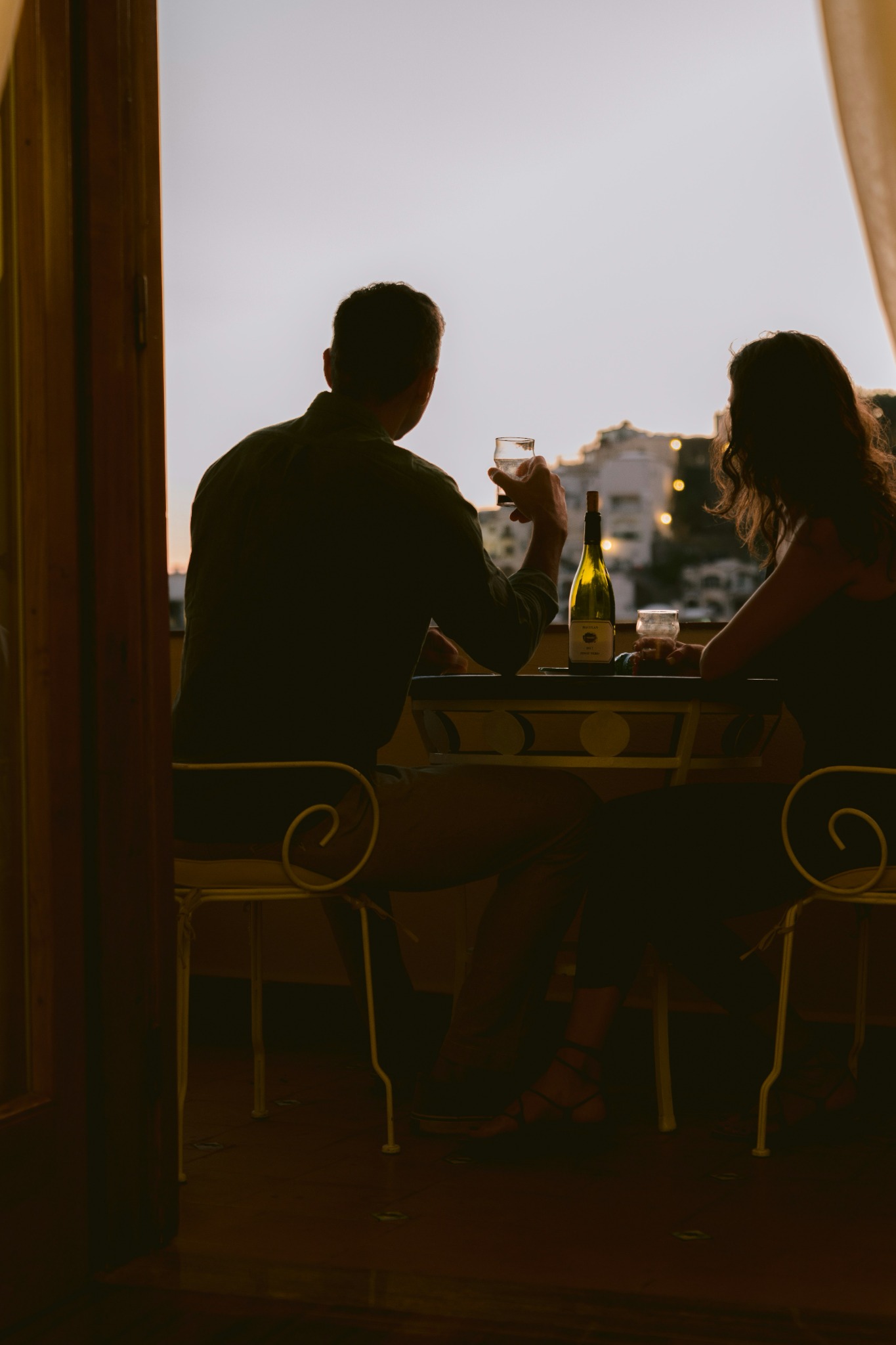 Couple enjoying drinks at sunset on a balcony